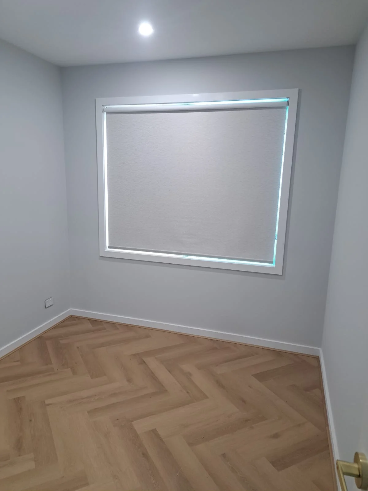 A lowered neutral blockout roller blind in supplied room photography
