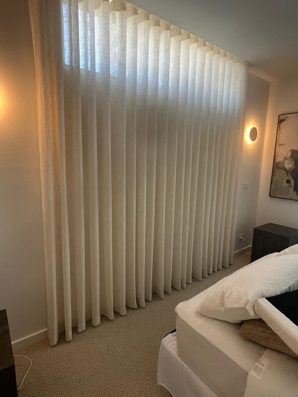 Full-height sheers in a warm bedroom with wall lights